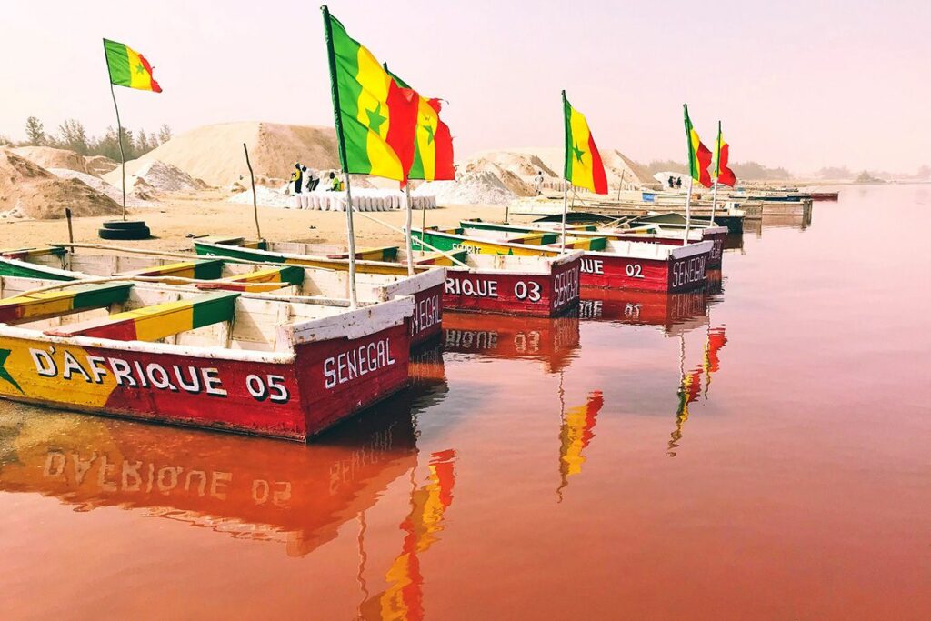 Plusieurs barques sur le lac rose avec des drapeaux du Sénégal