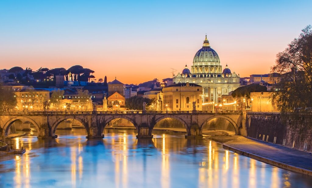 une photo du pont du Vatican la nuit, éclairé par des lumières orangées 